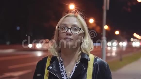 女孩晚上走在城市的街道上路过的车城市灯光视频的预览图