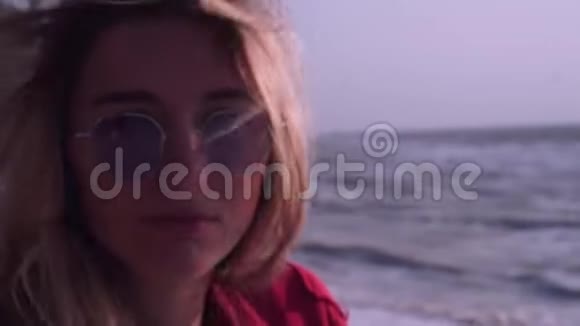 一个金发碧眼的漂亮女孩穿着一件红色T恤戴着一副不寻常的长方形的紫色眼镜视频的预览图