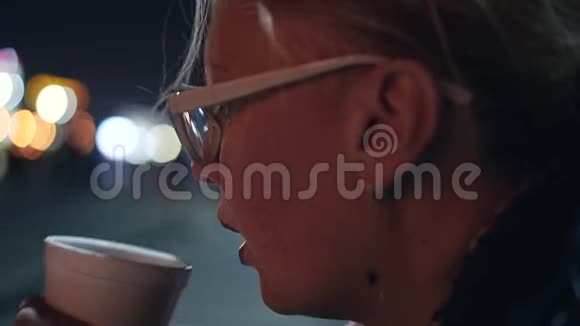 晚上坐在城市的海滨喝茶的女孩视频的预览图