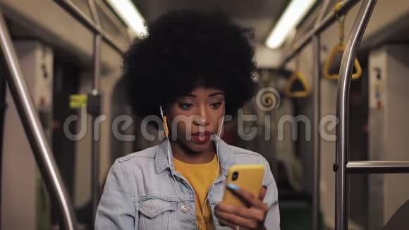 漂亮的非裔美国年轻女性在公共交通工具上使用智能手机她看录像微笑着视频的预览图