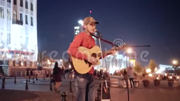 在大城市的夜街表演一个带吉他的街头音乐家良好的休息和舒适氛围视频的预览图
