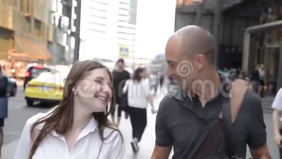 朋友们一男一女沿着市中心一条繁忙的街道散步微笑着交谈视频的预览图