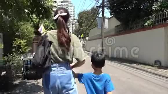 母亲正带着儿子在曼谷安静的街道上散步视频的预览图