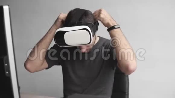 年轻人开始使用虚拟现实护目镜耳机坐在办公室里对着电脑连接技术视频的预览图