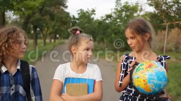 三个孩子在放学的路上笑这个女孩带着一个大地球仪再次上学快乐的孩子们视频的预览图