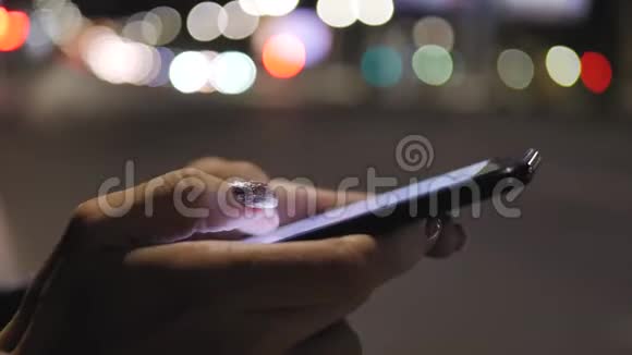晚上在城里关闭使用智能手机的女人女孩看着智能手机屏幕夜晚的背景视频的预览图
