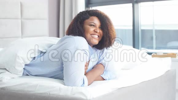 美丽的女人有快乐的表情躺在床上视频的预览图