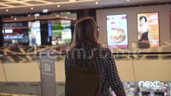 这个女孩在一个多层的购物中心从后面看到的视频的预览图