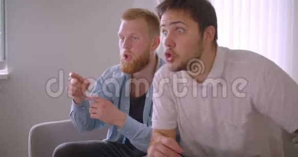 两位英俊的白种人成年男子在电视上观看体育节目他们坐在电视上感到愤怒和沮丧视频的预览图