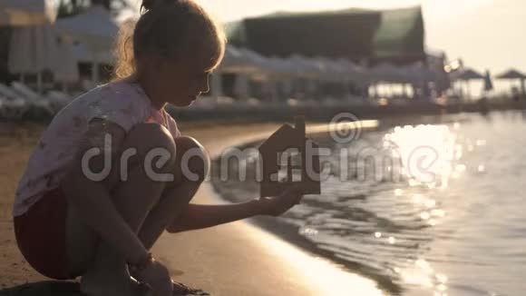 日落时女孩在海滩上拿着纸房子人梦想家庭房地产和家居理念儿童梦视频的预览图