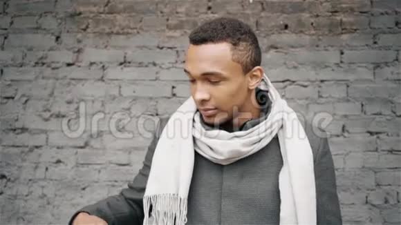 美国黑人在电话中讲话的慢镜头穿着外套和围巾英俊的非裔美国人视频的预览图