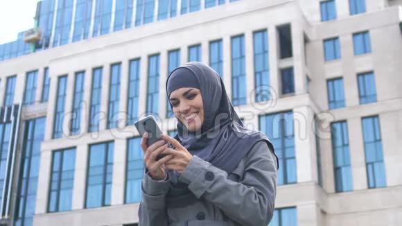 兴奋的穆斯林女孩在电话中读到关于招聘或进入大学的信息视频的预览图