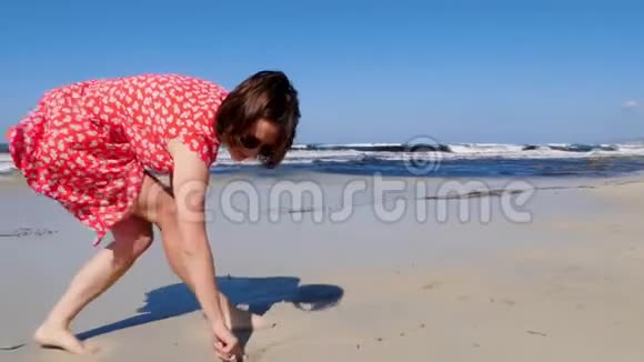 年轻快乐的女士在海边沙滩上画画强烈的风浪冲击着海岸刮风慢动作视频的预览图