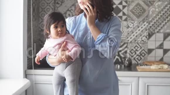 美丽的女人手里拿着一个婴儿通过电话聊天视频的预览图