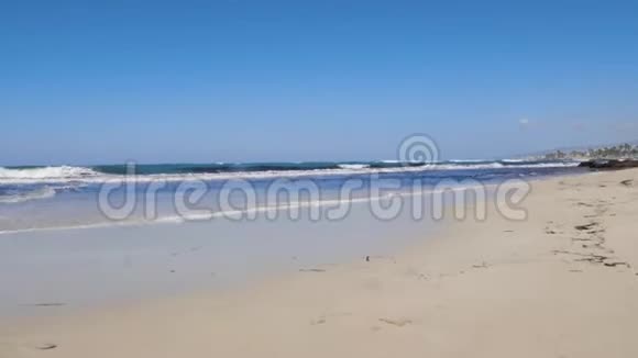 年轻快乐的女人沿着海边奔跑摆姿势强烈的波浪撞击海岸穿红色连衣裙和戴墨镜的女人视频的预览图