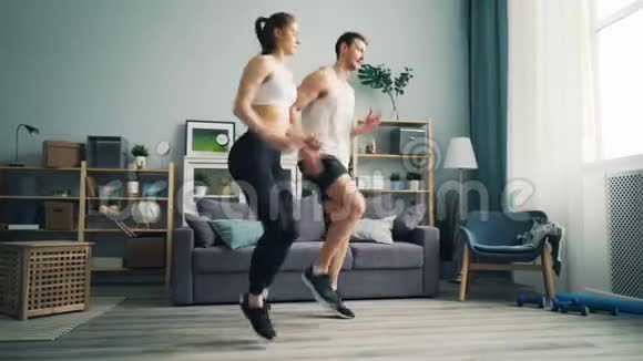 夫妻两个男人和女人在家里当场跑步移动手臂锻炼视频的预览图