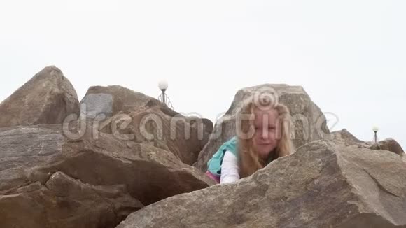 女孩学龄前儿童在海滨的大石头上玩耍视频的预览图