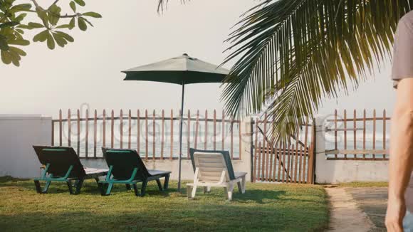 后景成功的男性游客慢慢走上椅子和栅栏享受史诗般的夏季海洋度假海滩景观视频的预览图