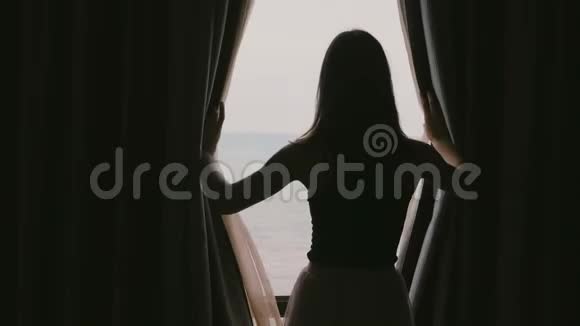 年轻快乐轻松的美女在酒店房间打开窗帘欣赏史诗般的海景微笑缓慢的动作视频的预览图
