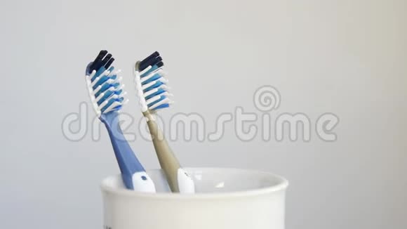 牙刷在旋转牙刷杯特写灰色背景视频的预览图