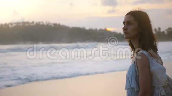 年轻美丽放松的白人旅游妇女在日落时欣赏热带海洋海滩美景的中景肖像视频的预览图