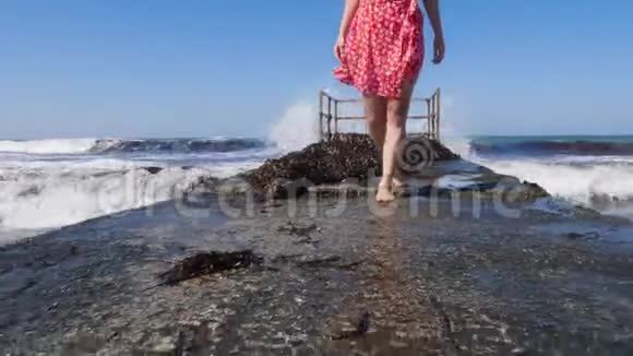 年轻的美女赤脚走在海上码头上海浪拍打着码头腿靠近视野视频的预览图