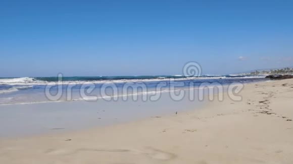 年轻快乐的女人沿着海边奔跑摆姿势强烈的波浪撞击海岸穿红色连衣裙和戴墨镜的女人视频的预览图
