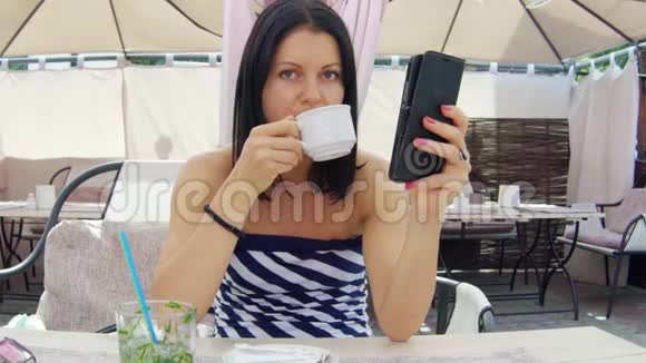 美女在咖啡馆喝茶看着电话视频的预览图