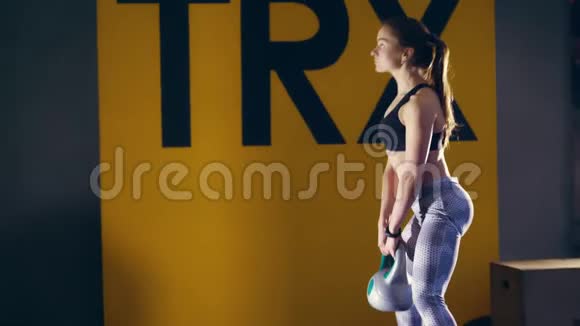 迷人的金发女人穿着紧身裤和上衣用水壶铃做运动做交叉健身运动的肌肉妇女视频的预览图