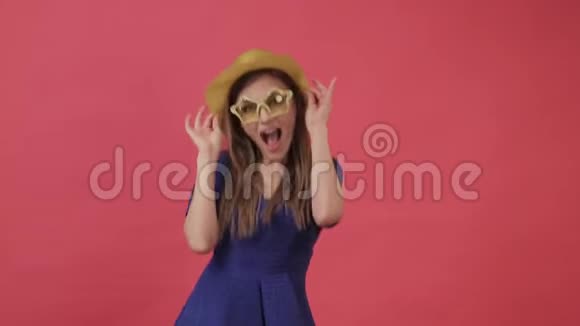 美丽的女孩穿着一件连衣裙戴着黄色的眼镜以星星的形式跳舞紫色背景工作室视频的预览图