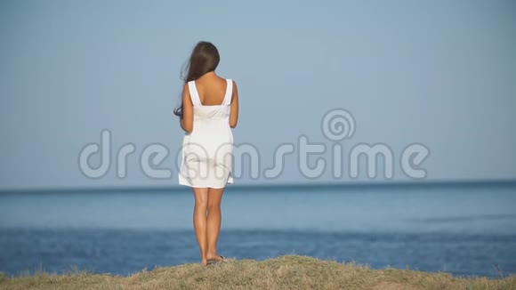 穿着白色连衣裙和太阳镜的女人站着着视频的预览图