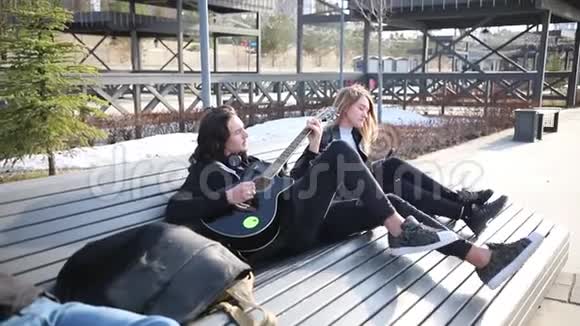 年轻夫妇坐在长凳上一个弹吉他的男人视频的预览图