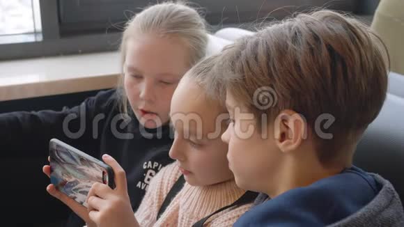 青少年团队在快餐店的餐桌上看手机视频的预览图