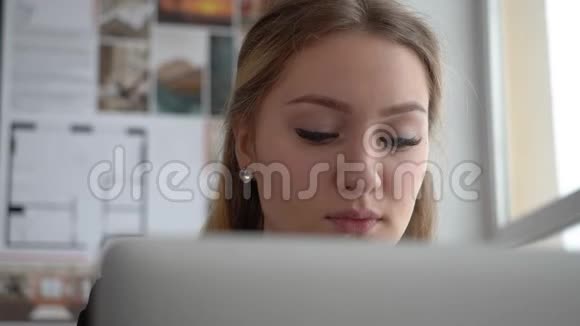 一个漂亮的年轻女商人设计师在她的办公室里用笔记本电脑工作视频的预览图