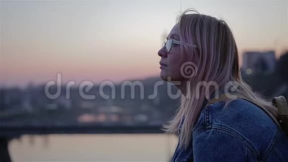 美丽的红日落在河上女孩坐在水边望着远处美丽的电影框架视频的预览图