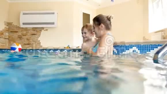 4k视频快乐微笑年轻母亲与3岁幼儿男孩游泳和在游泳池在健身房玩耍视频的预览图