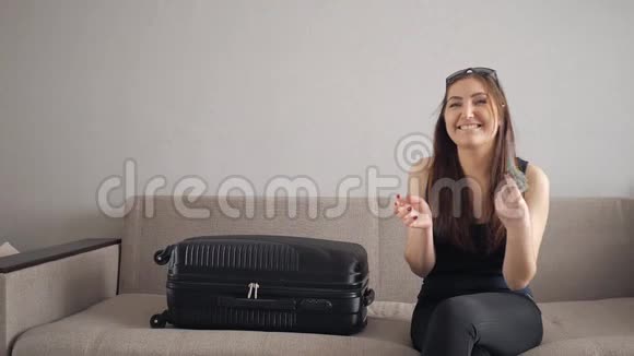带着手提箱的女孩慢动作坐在沙发上把美元扔了起来视频的预览图