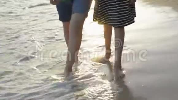 亚洲女孩和她的妹妹手拉手一起悠闲地在海滩上散步海浪在海岸上冲刷视频的预览图