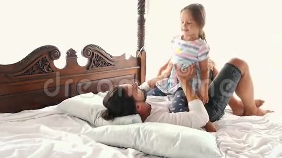 幸福的家庭我的小女儿跳到父亲的手臂上他们躺在床上视频的预览图