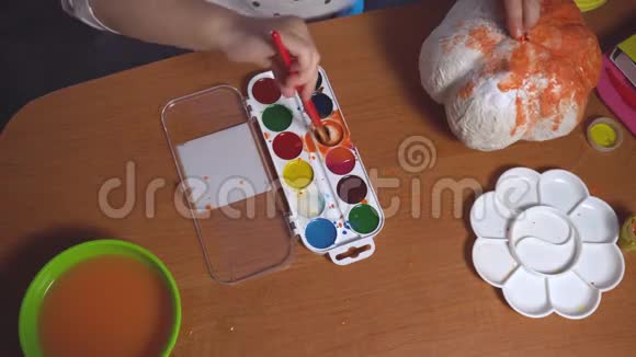 桌面上有小女孩为一些工艺品上色视频的预览图