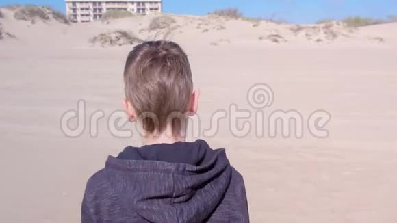 小男孩正走在沙滩上到沙丘后看户外活动视频的预览图