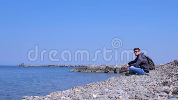 在阳光明媚的春天人们坐在海石滩上欣赏海景视频的预览图