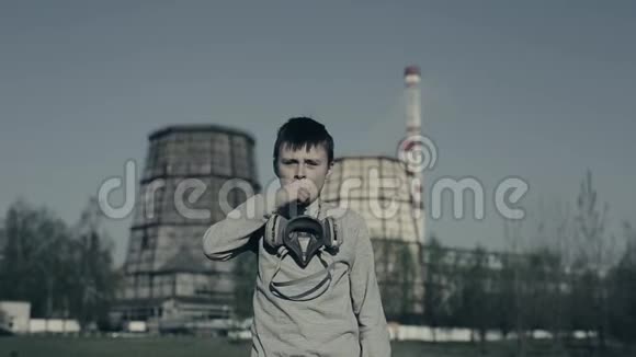 年轻的男孩咳嗽戴着污染面具反对工厂烟囱这个男孩因为污染而窒息视频的预览图