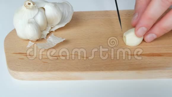 女性用黑色陶瓷刀在木制厨房板上切割白色大蒜视频的预览图