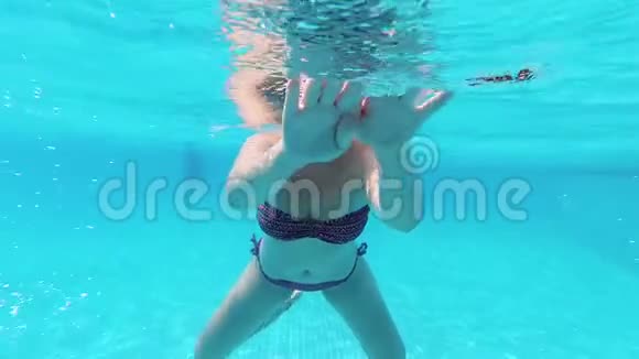 年轻女子在清澈的蓝色游泳池里水下游泳慢镜头视频的预览图