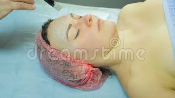 戴手套的美容师在女人的脸上戴上化妆面具侧视图视频的预览图