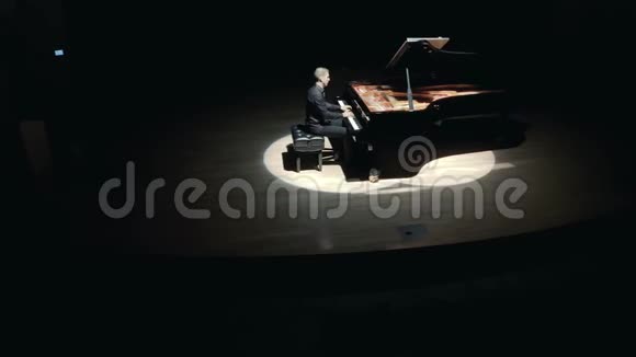 舞台上的大钢琴一个穿着黑色西装的优雅男子在音乐厅的舞台上演奏大钢琴视频的预览图