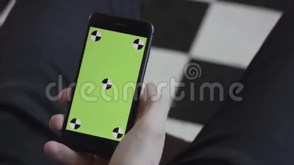 男士双手使用带有绿色屏幕的移动智能手机侧肩观看库存录像接近人类滚动视频的预览图
