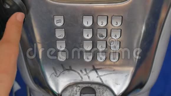 这个女孩用旧金属破旧的灰色电话在城市街道上打电话电话亭里的老式电话视频的预览图