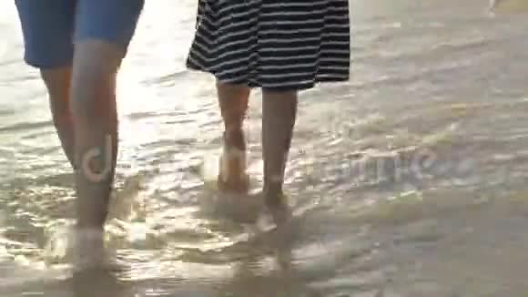 亚洲女孩和她的妹妹手拉手一起悠闲地在海滩上散步海浪在海岸上冲刷视频的预览图